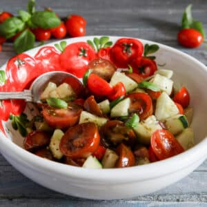 Tomato salad in a white bowl with tomatoes on it.