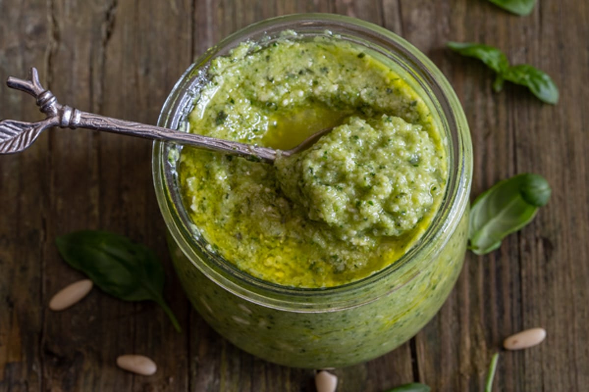 Zucchini pesto in a glass jar and on a spoon.