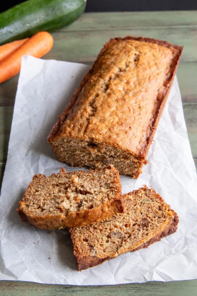 Carrot bread with two slices cut on parchment paper.