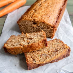 Carrot bread with two slices cut on parchment paper.