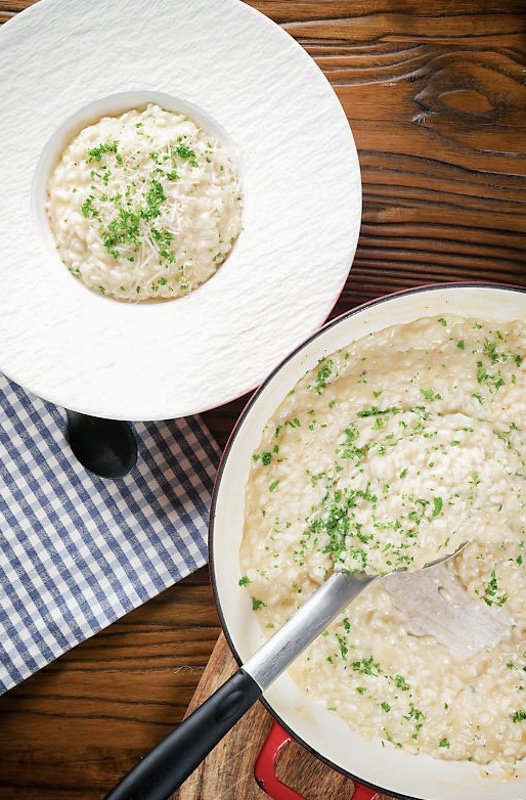 Risotto in a pan and some in a white bowl.