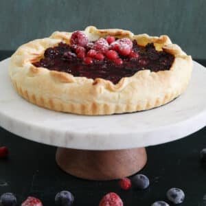 Ricotta crostata on a white cake stand.