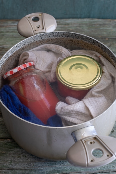 The jars in a big pot with towels and covered in water.