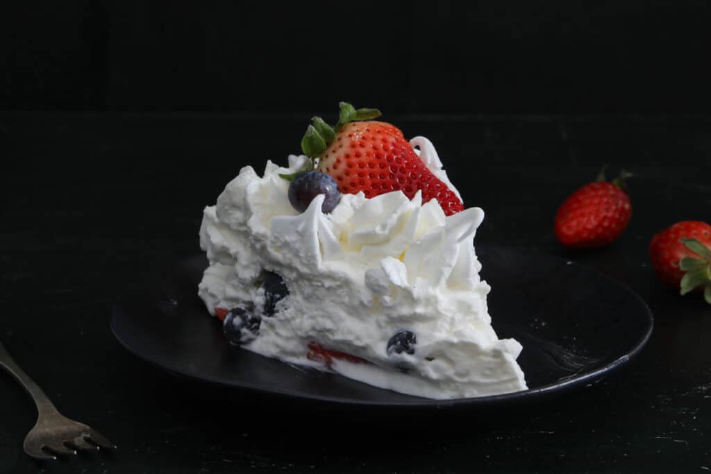 A slice of cake on a black plate.