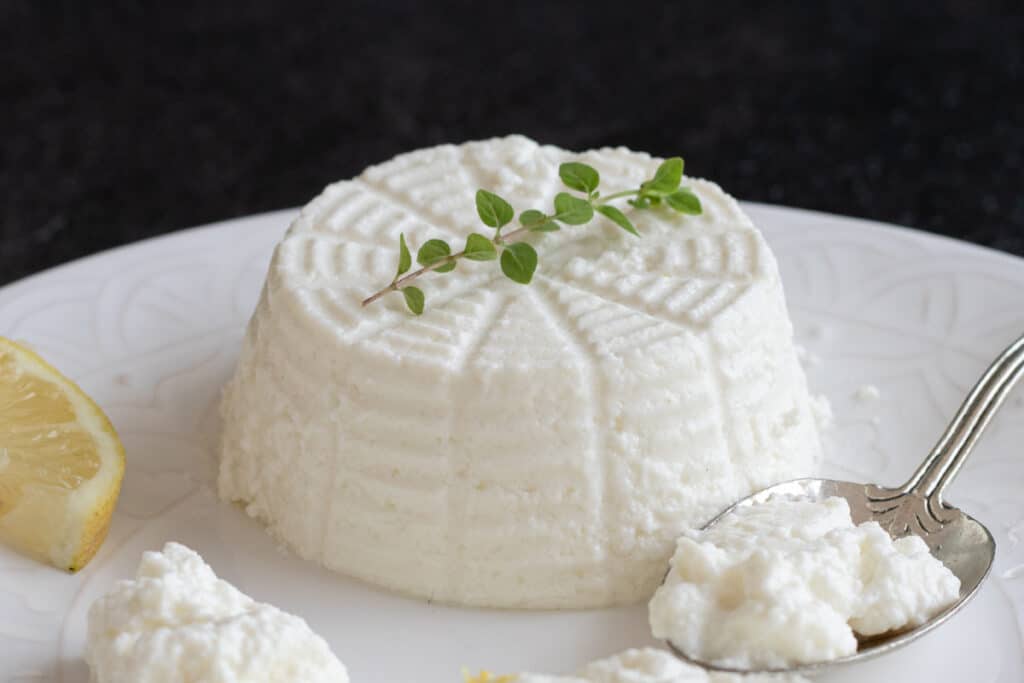 Ricotta on a white plate and some on a spoon.