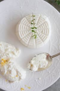 Ricotta on a plate with some on a spoon.