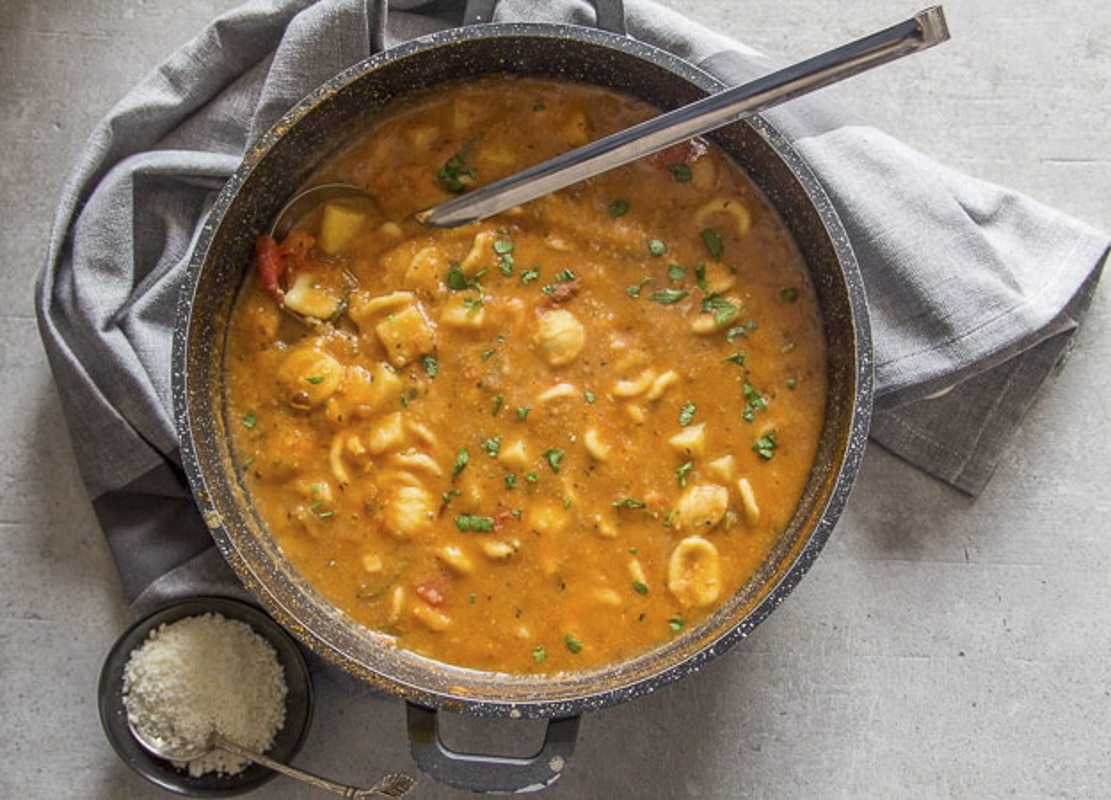 Hearty chickpea soup in a black pot.