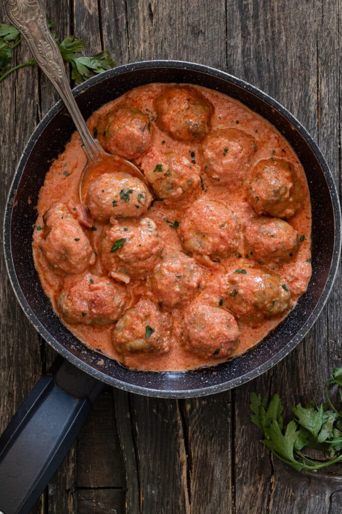 Meatballs in a cream sauce in a black pan.