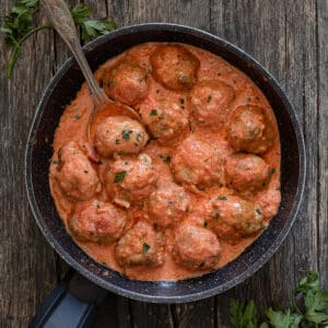 Meatballs in a cream sauce in a black pan.