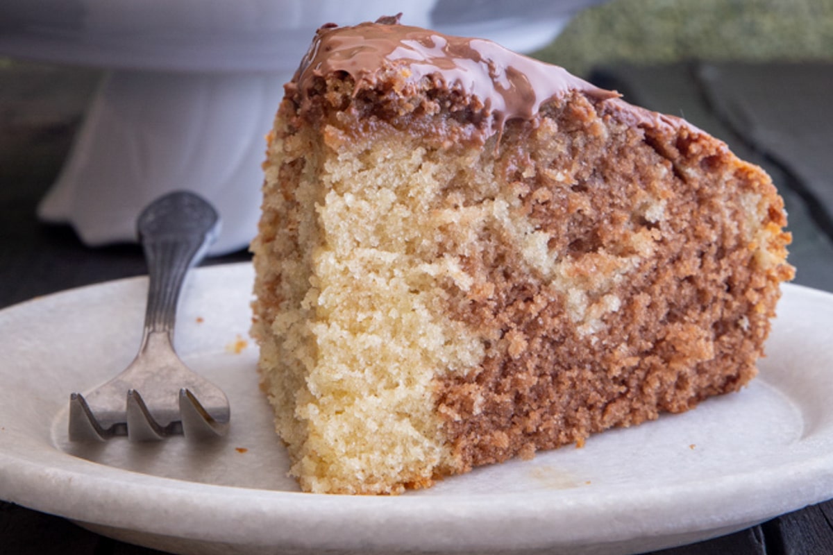 A slice of marble cake on a white plate with a fork.