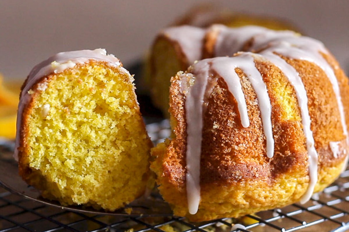 Orange olive oil cake on a wire rack with a slice cut.