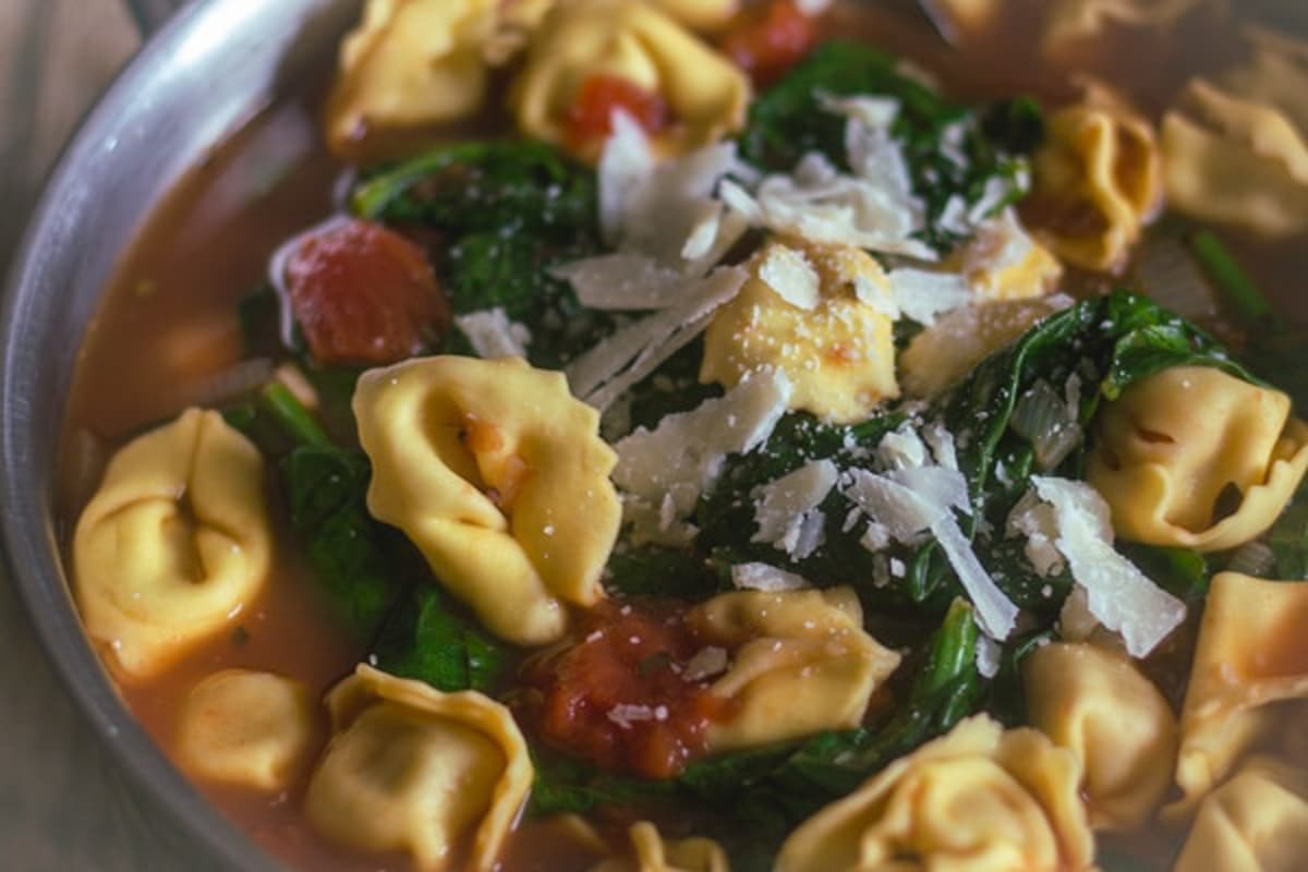 Tortellini soup in a silver pot.