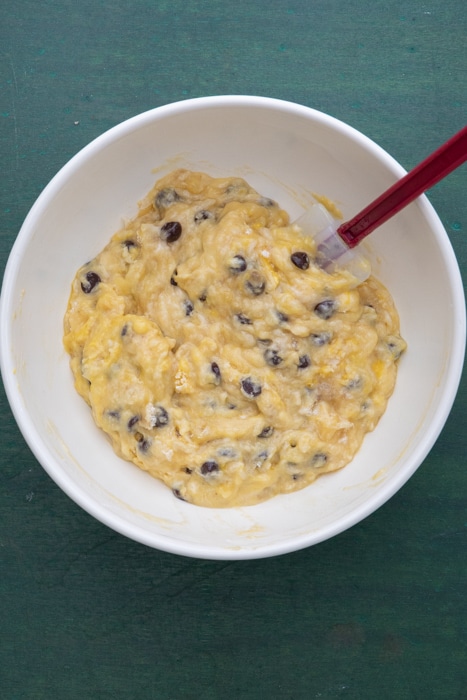 Wet and dry ingredients mixed in a white bowl with a spatula.