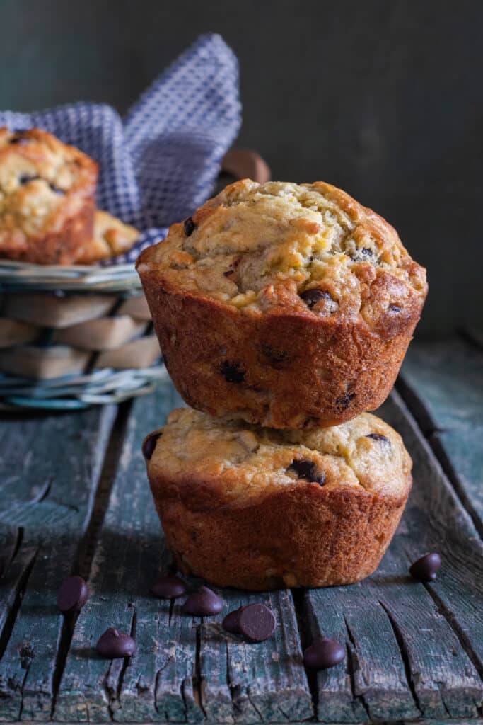 Two muffins stacked with some in a blue basket.