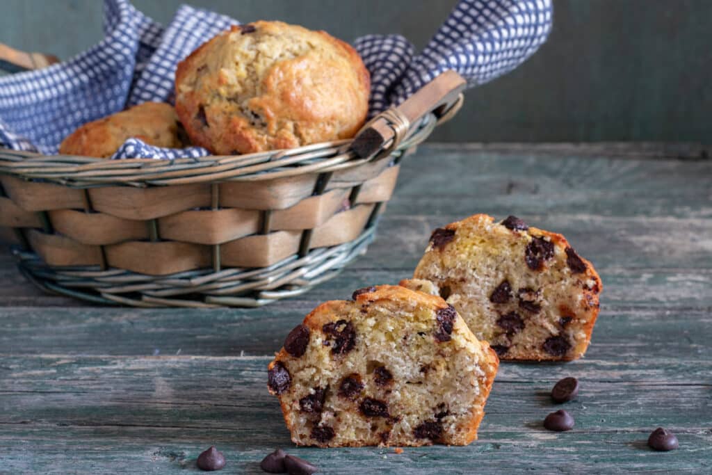 Banana muffins in a basket with one cut in half.