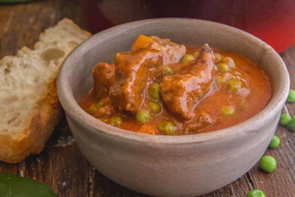 Beef stew with peas in a brown bowl.