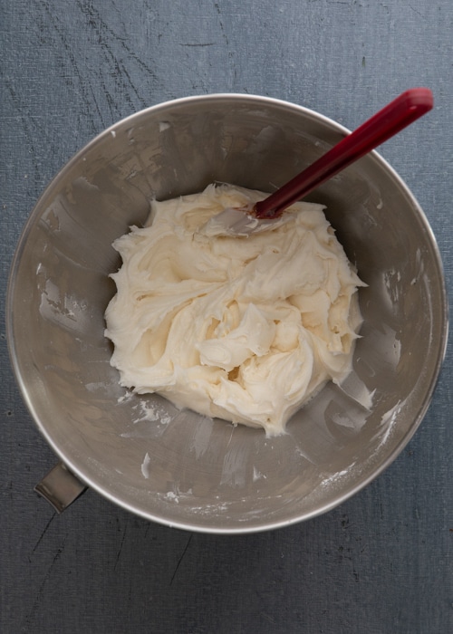 The cream cheese frosting in the a silver bowl.