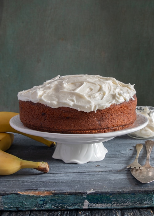 The banana cake on a white cake stand.