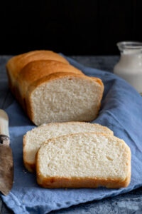 Bread on a blue napkin with two slices cut.