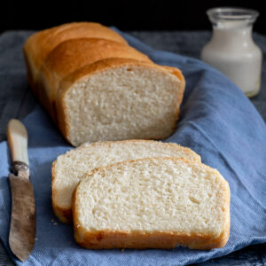 Bread on a blue napkin with two slices cut.