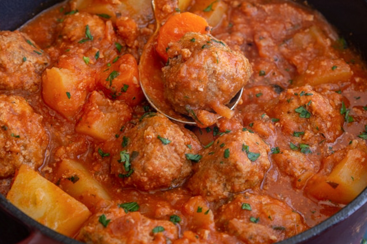 Meatball stew in a black pot.