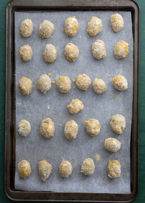 The breaded olives on a baking sheet.