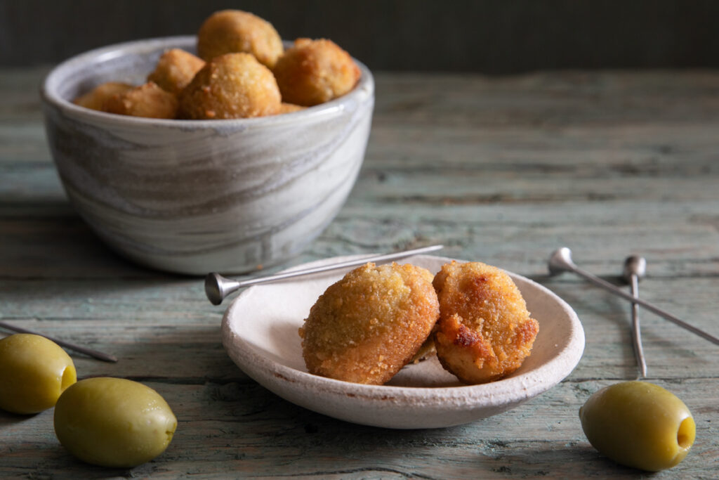 Olive ascolane in a grey bowl and two in a white dish.