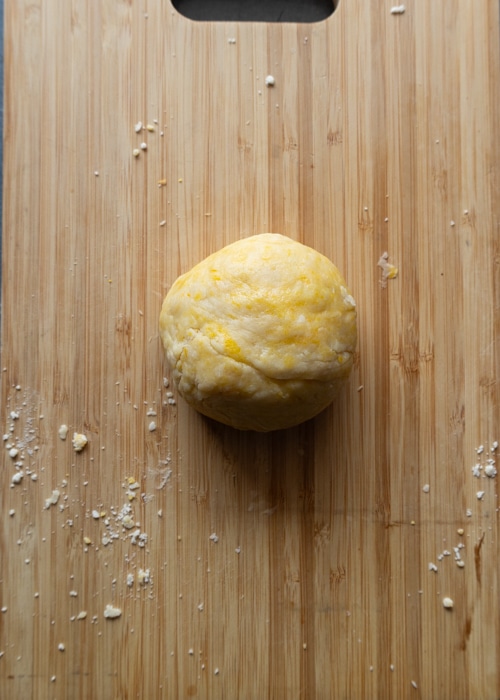 The dough formed into a compact dough on a wooden board.