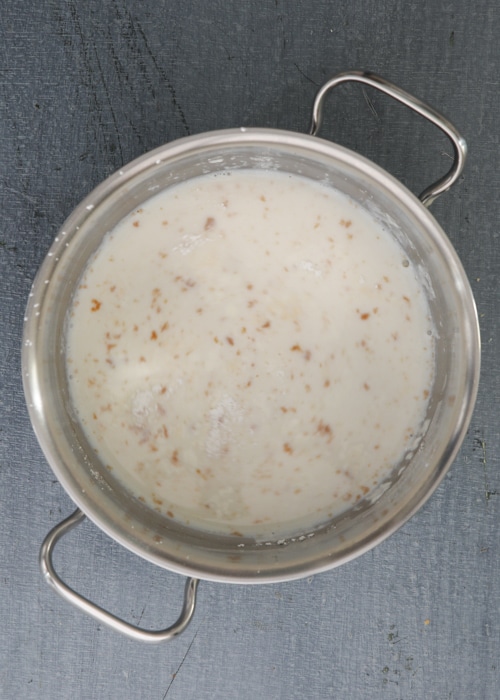 Heating the milk in a silver pot.