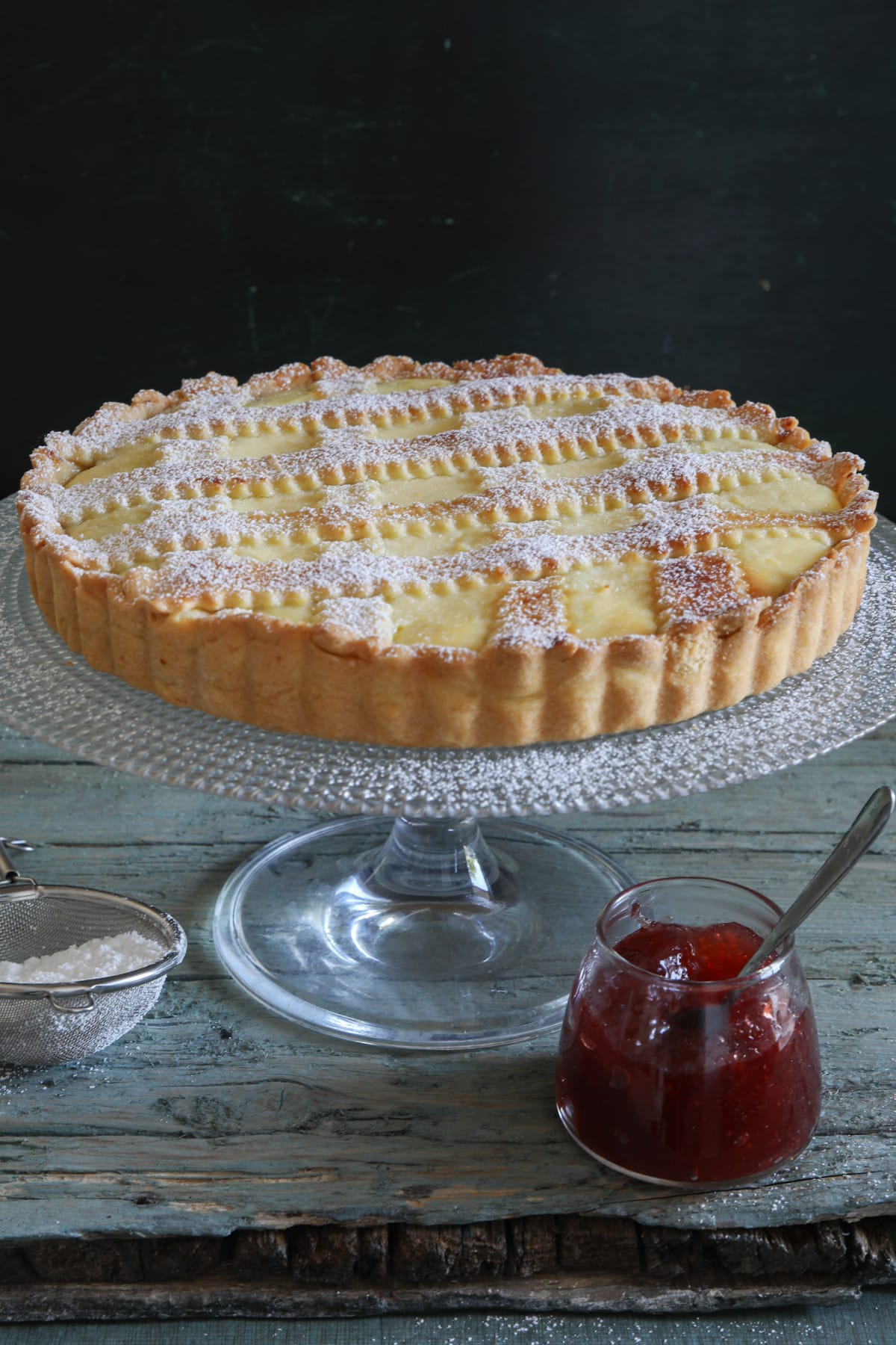 A simple Italian crostata on a glass cake stand.