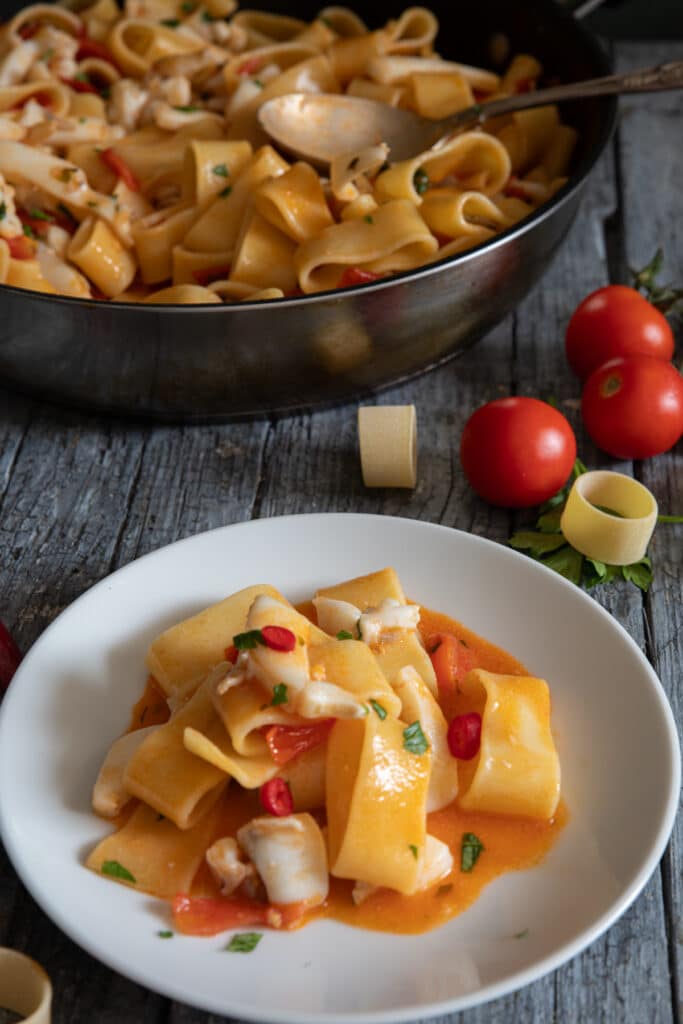 Pasta in the pan and some on a white plate.