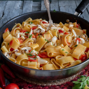 The calamarata pasta in a black pan with a silver spoon.