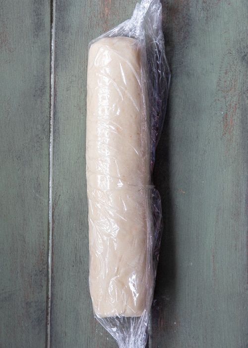 The dough formed into a log and wrapped in plastic wrap.