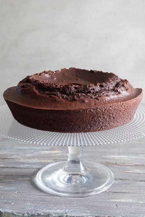 Mocha ricotta cake on a glass stand.