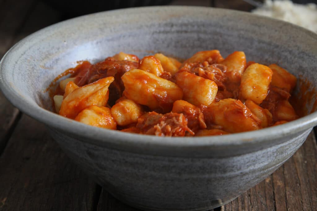 Gnocchi with sauce in a blue bowl.