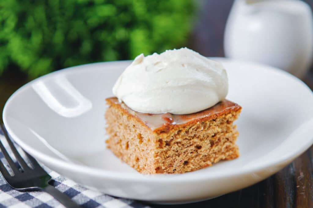 A slice of sticky toffee pudding with cream on top.