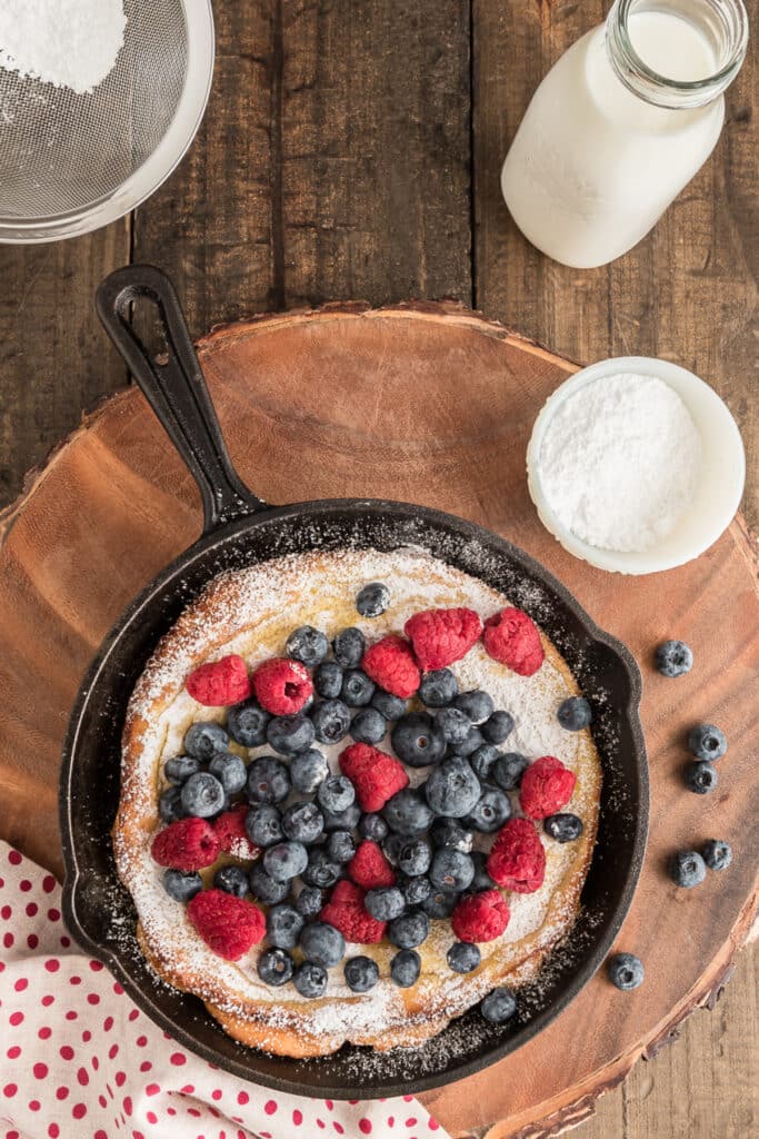 Berry puff in a black pan on wooden board.