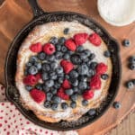 Berry puff in a black pan on wooden board.