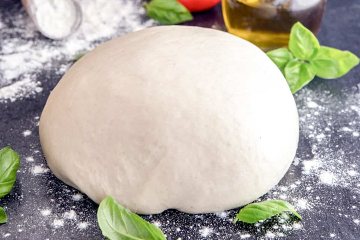 Pizza dough on a black board.