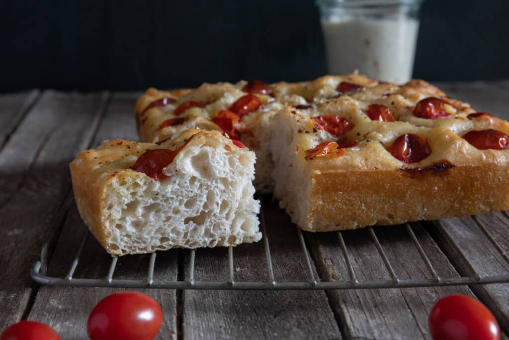 Focaccia on a wire rack with a slice cut.