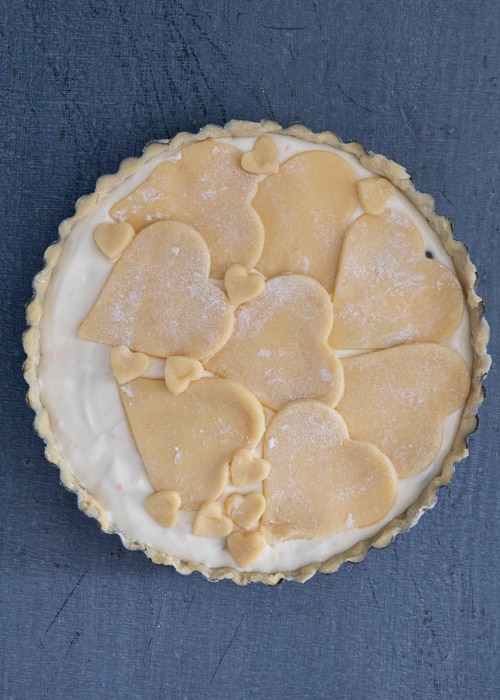 Placing the cut out pastry on top and brushing with milk before baking.