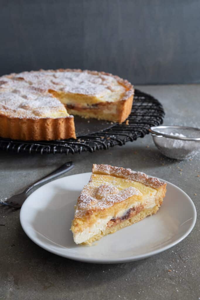 Crostata on a wire rack and a slice on a plate.