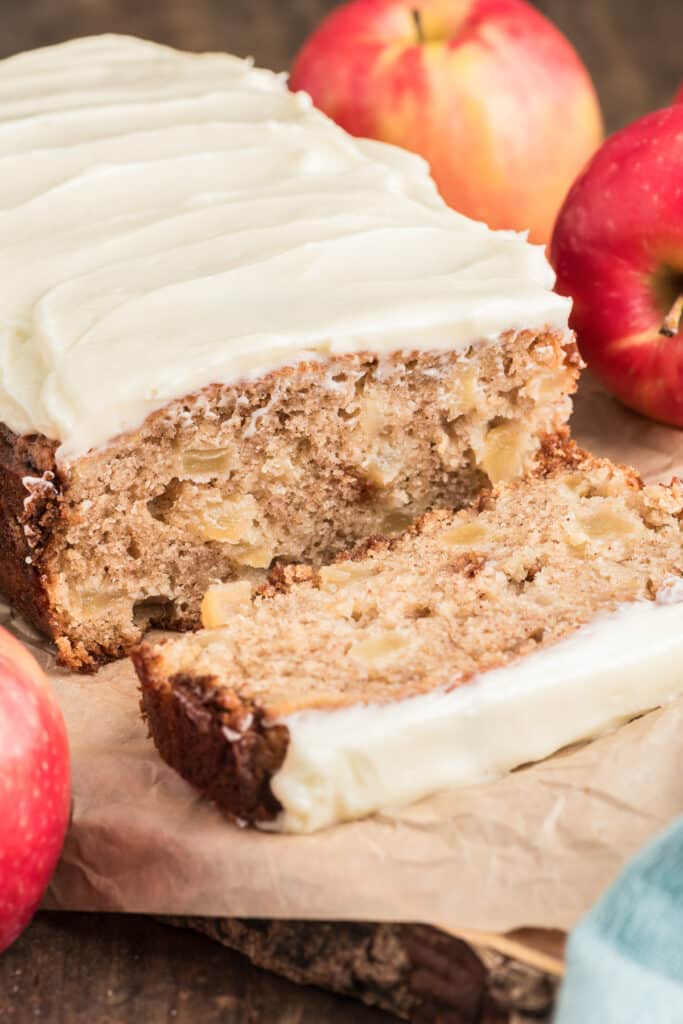 Apple bread with a slice cut on a wooden board.