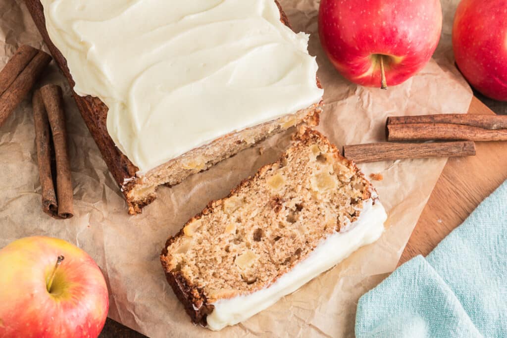 Apple bread with a slice cut on a wooden board.