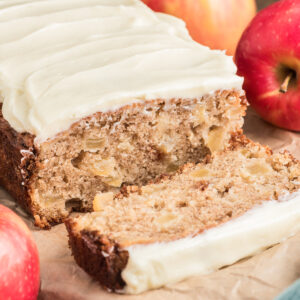 Apple bread with a slice cut on a wooden board.