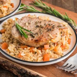 The pork chop and rice on a white plate.