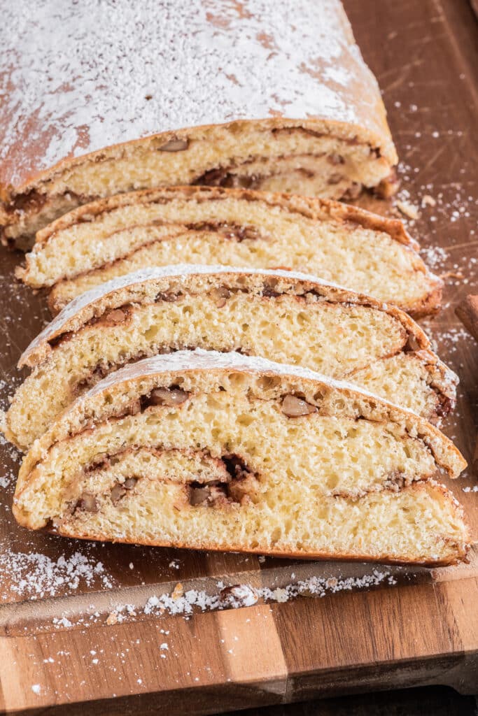 Cinnamon swirl loaf with four slices on a wooden board.