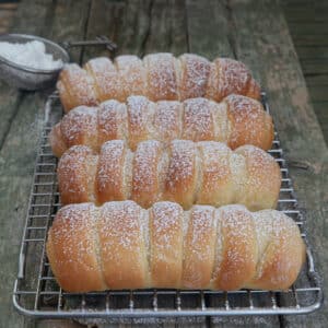 Four Easter buns on a wire rack.