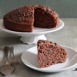 Chocolate cake with a slice on a white plate.