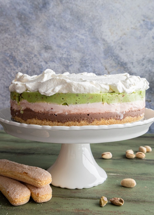 The spumoni ice cream cake on a white cake stand.